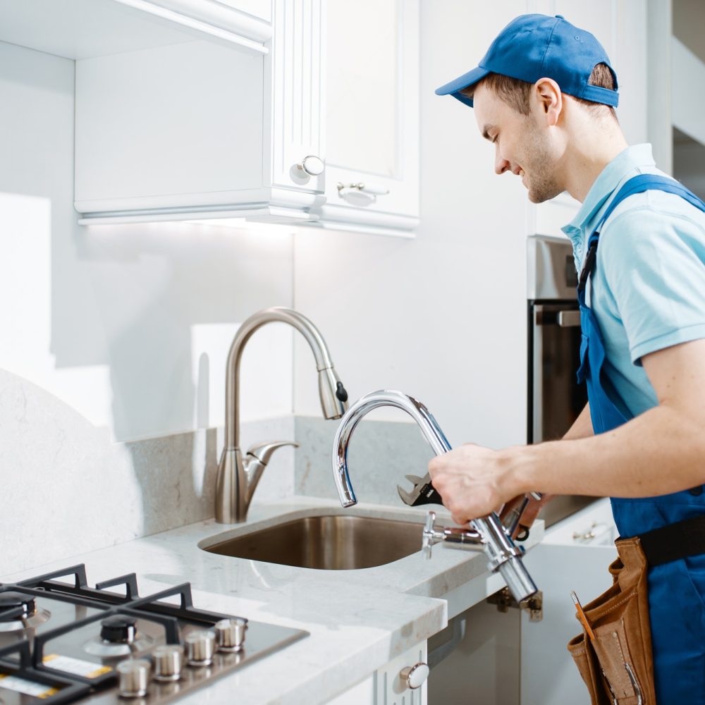 plumber-in-uniform-changes-faucet-in-the-kitchen.jpg